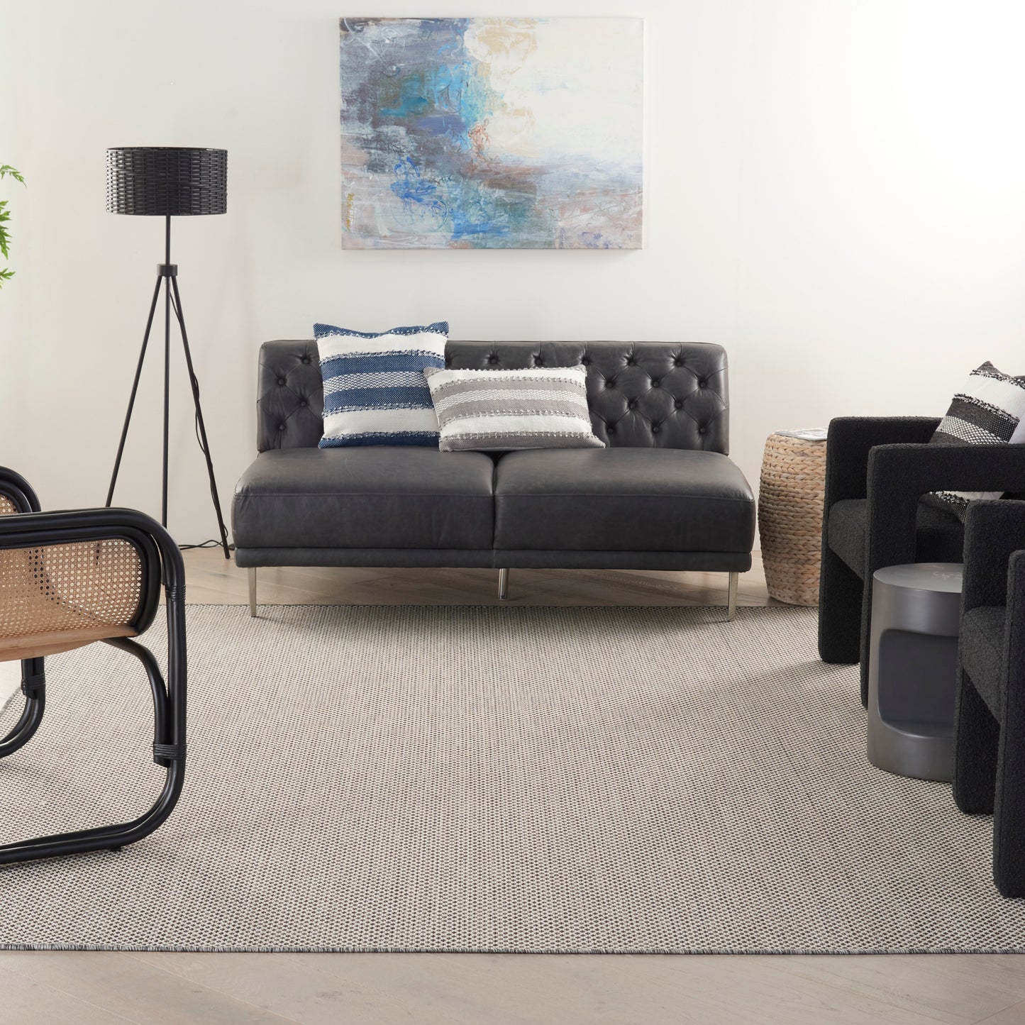 Dark gray tufted leather loveseat with metal legs, navy and white striped cushions, contemporary living room.