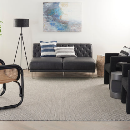 Dark gray tufted leather loveseat with metal legs, navy and white striped cushions, contemporary living room.