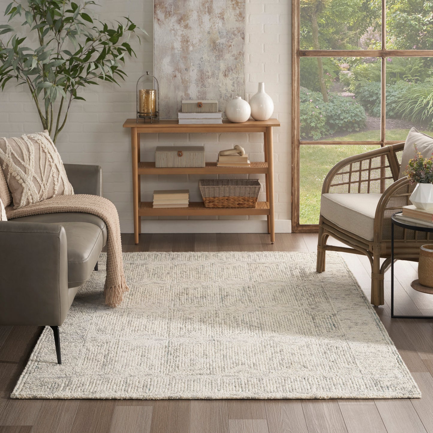 Cream woven area rug on wood floor in a cozy living room with gray sofa, wicker chair, and wooden console.