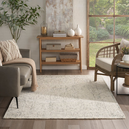Cream woven area rug on wood floor in a cozy living room with gray sofa, wicker chair, and wooden console.