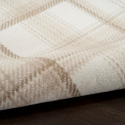 Close-up of a plush beige plaid rug with light tan checks, folded edge on dark wood floor.