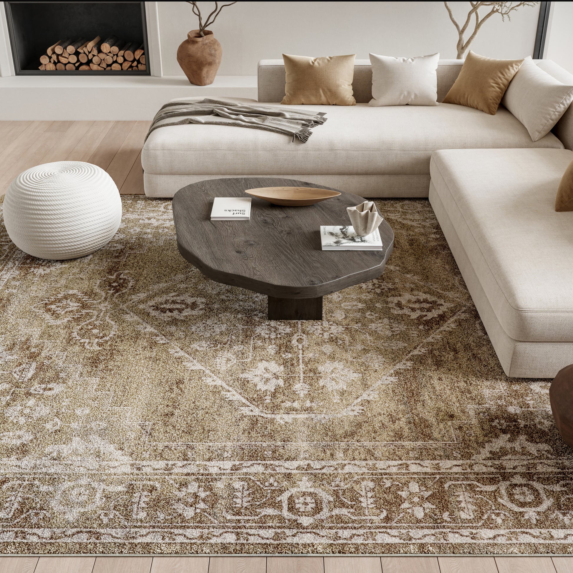 Modern living room with beige sectional, dark wood round coffee table, white knitted pouf, and patterned beige rug.