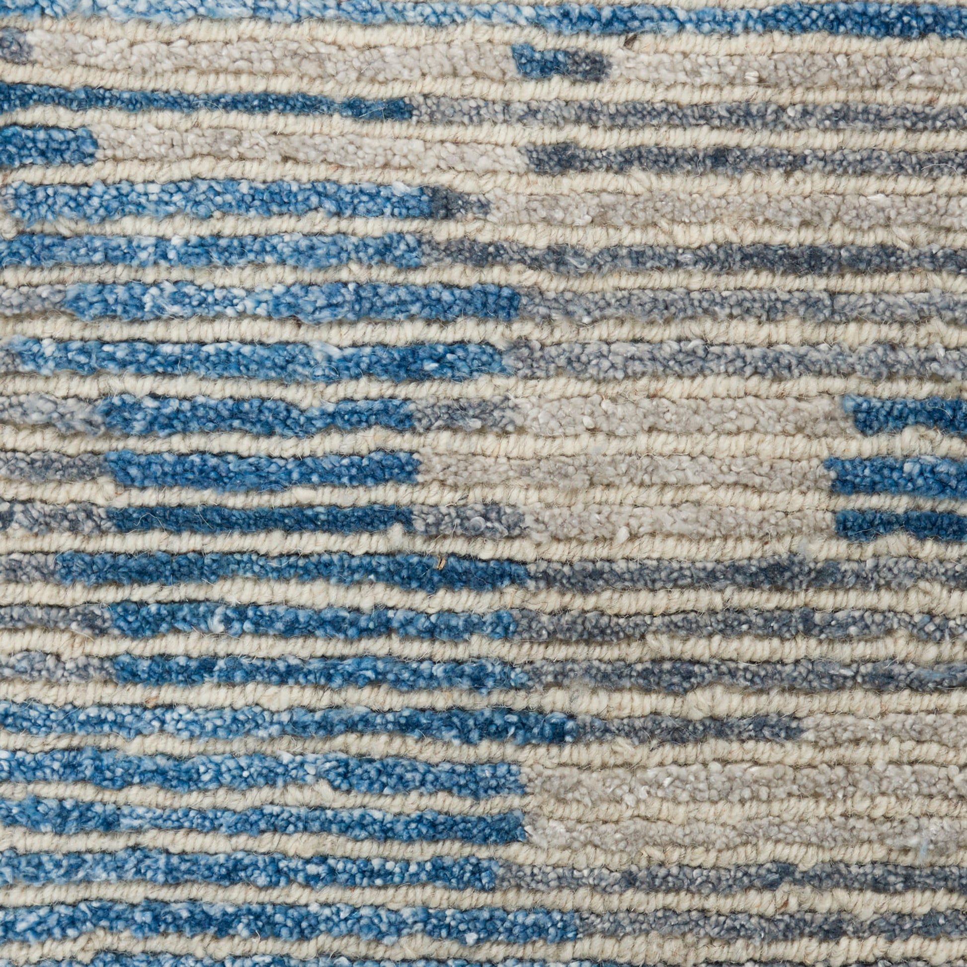 Close-up of a blue and cream woven rug with textured loops and irregular horizontal stripes.