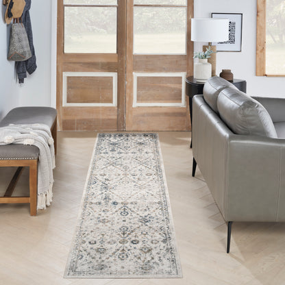 Cream runner rug with blue-gray medallions on a light wood floor beside a gray leather sofa in a modern farmhouse living room.