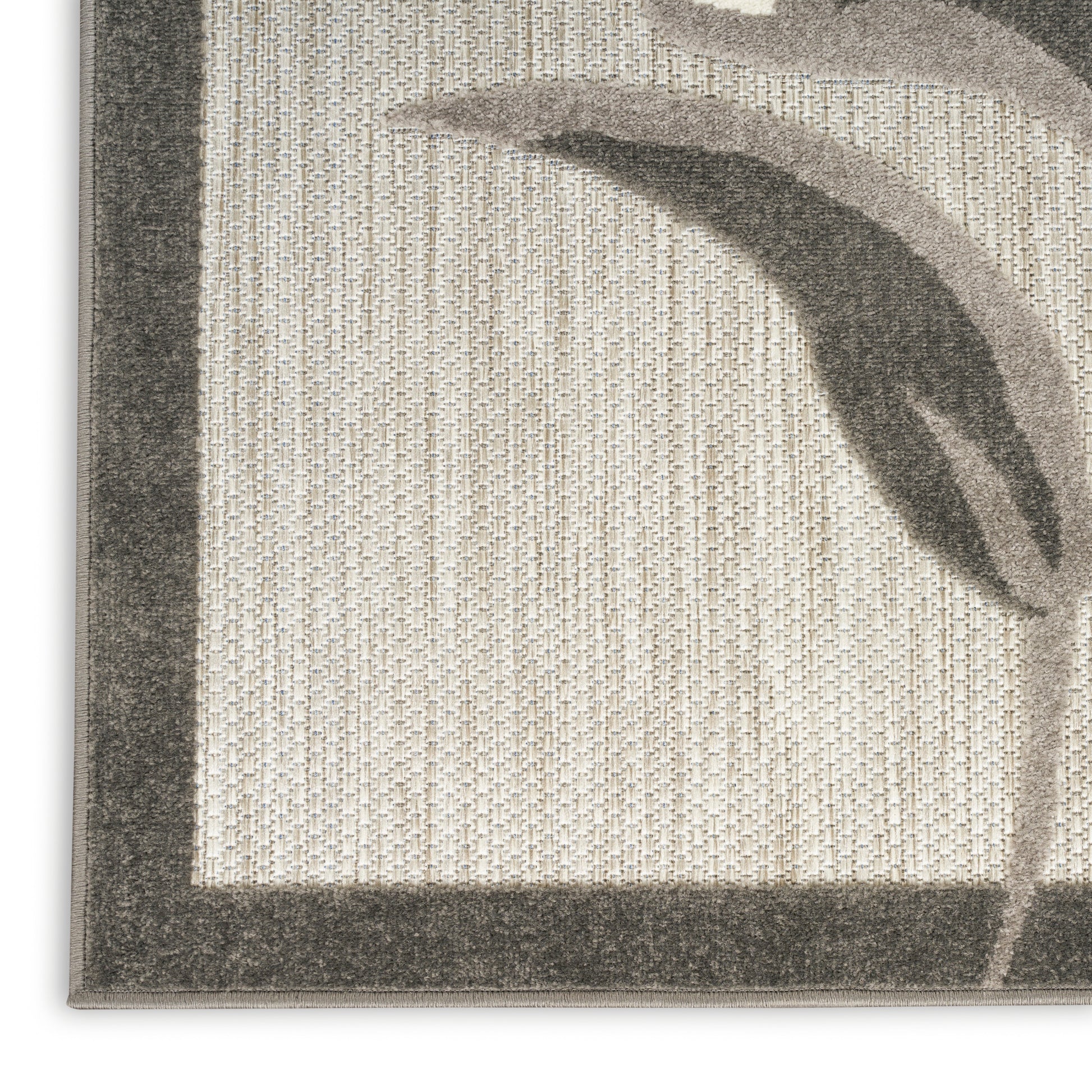 Beige woven rug close-up with gray border and curved leaf motif, textured pile.