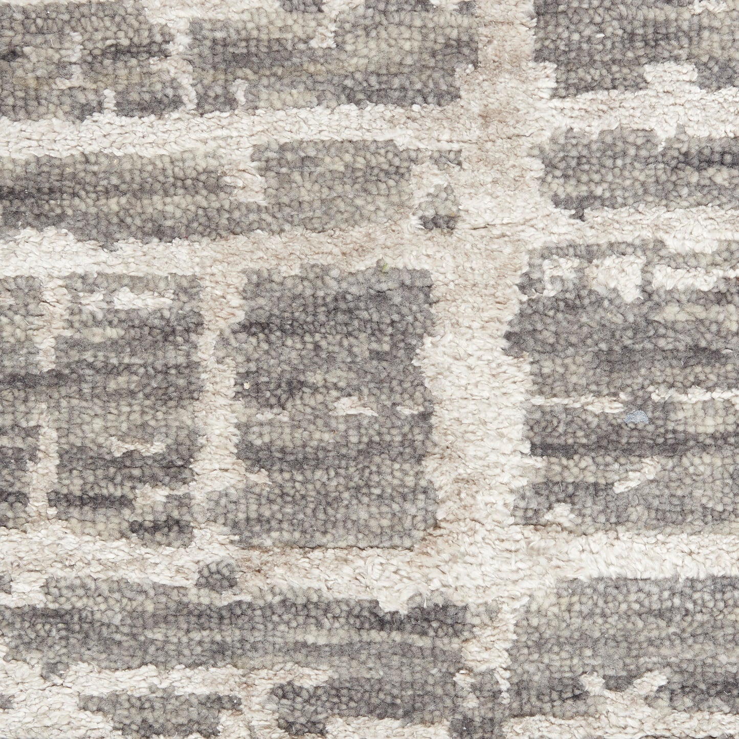 Close-up of a neutral grey and ivory geometric patterned shag rug with chunky textured pile.