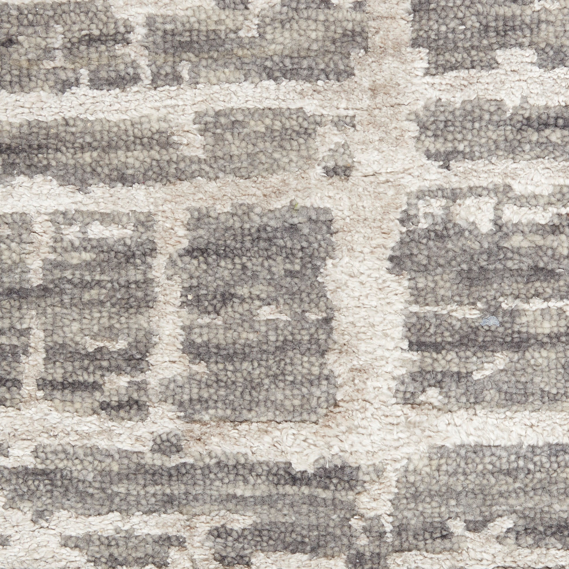 Close-up of a neutral grey and ivory geometric patterned shag rug with chunky textured pile.