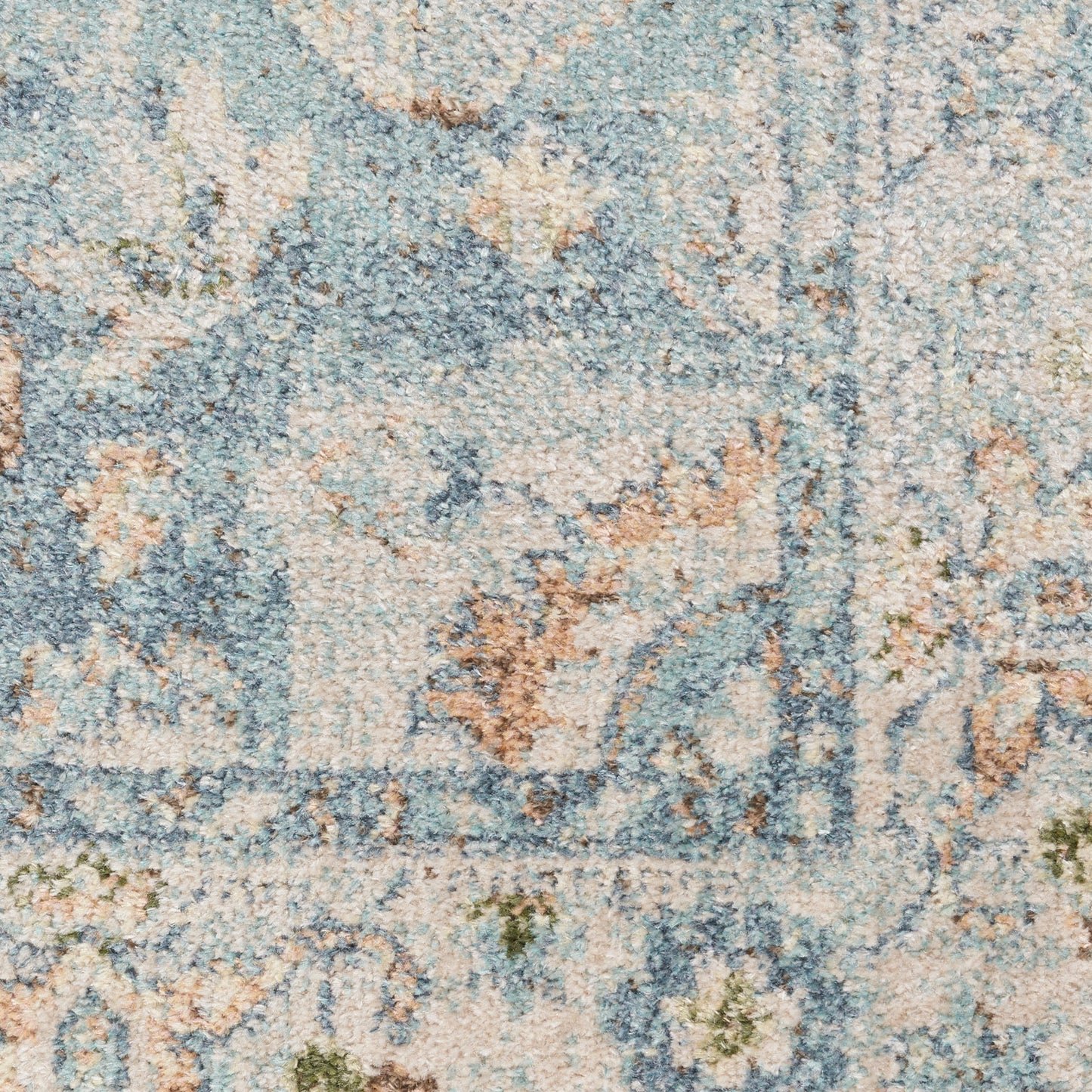 Close-up of a blue and beige floral-patterned rug with distressed texture and subtle green accents.