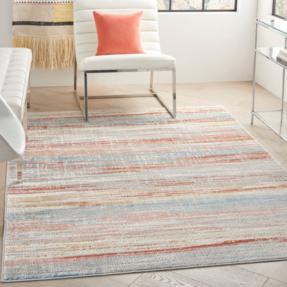 Woven striped area rug in pastel blues, peaches and corals, set in a bright modern living room.