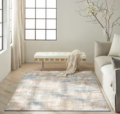 Rectangular area rug in blue, beige and gray tones with a soft texture, placed in a modern living room.