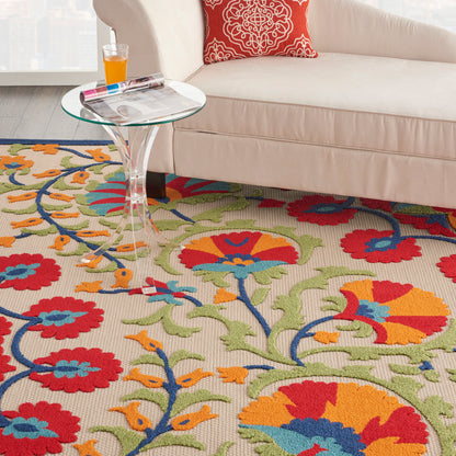 Colorful floral area rug with red, orange, blue and green flowers; glass-top side table beside a beige sofa.