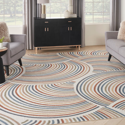 Living room with swirl-pattern rug in blue, rust and beige; gray armchairs and a black cabinet with gold handles.