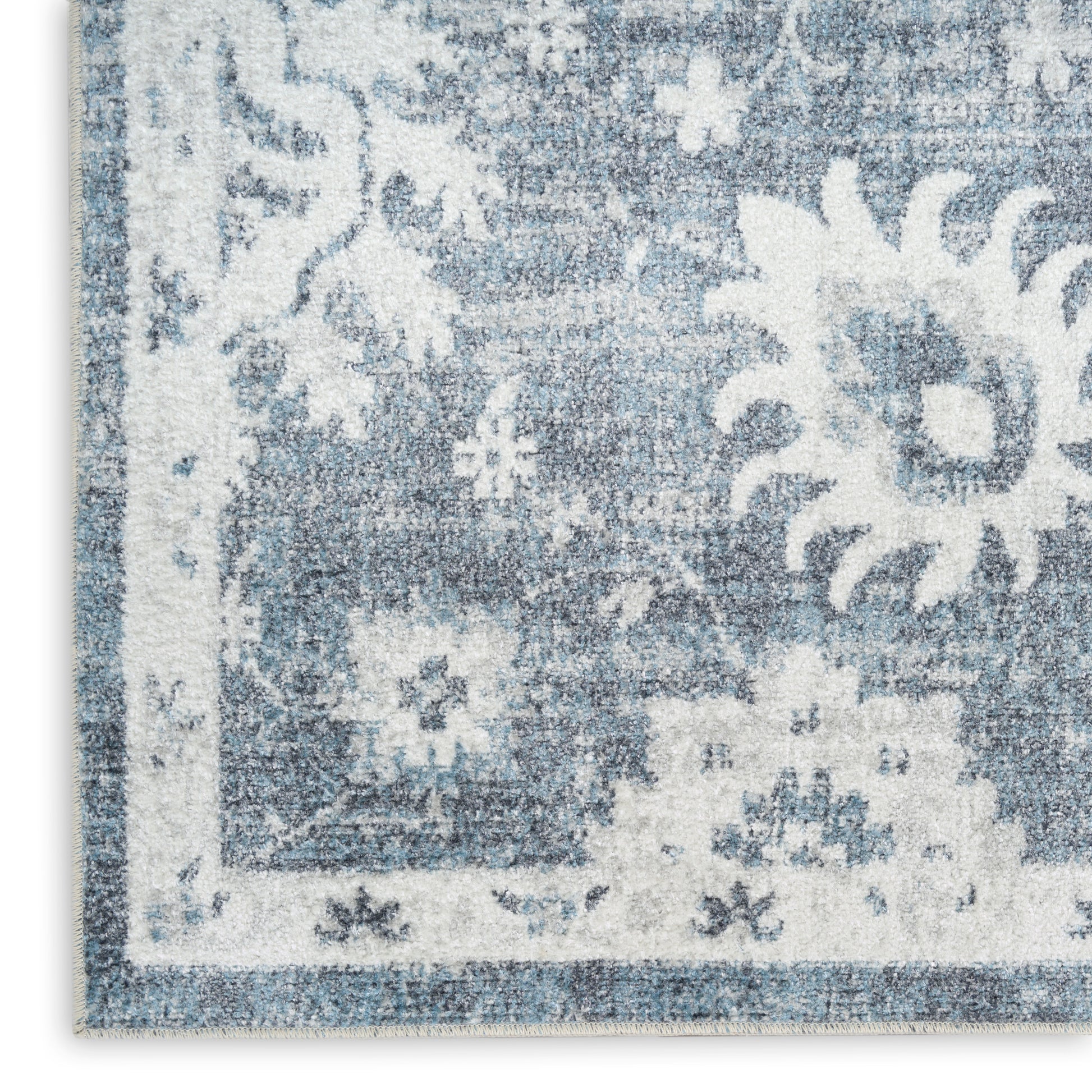 Blue and white oriental-style rug with floral motifs and decorative border; soft textured pile.