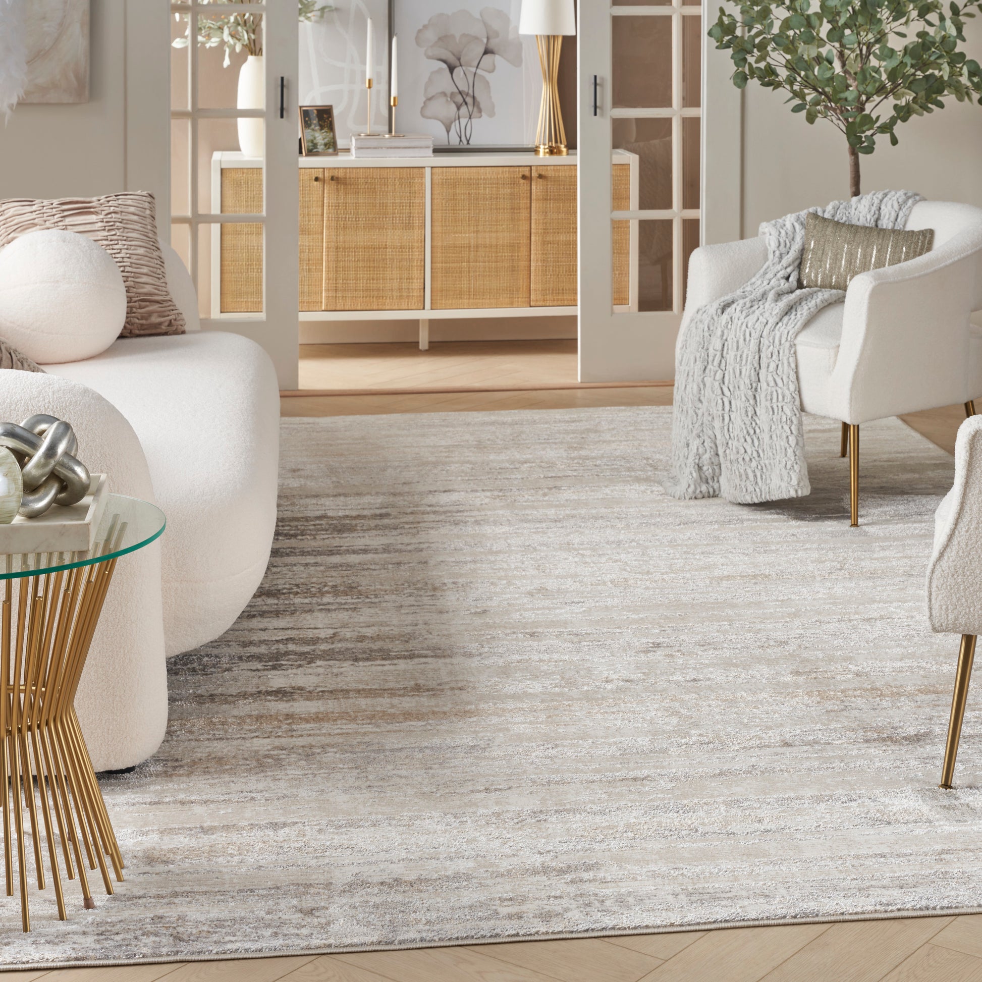 Light gray and ivory patterned area rug in a modern Scandinavian living room with beige sofa and glass coffee table.