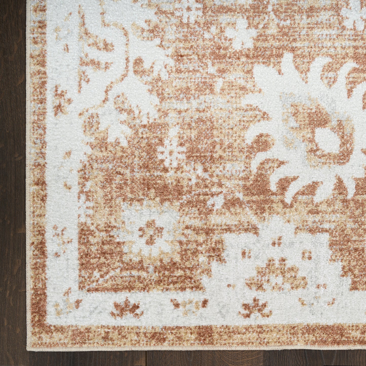 Rust-orange and cream floral area rug with ornate border; rectangular corner view.