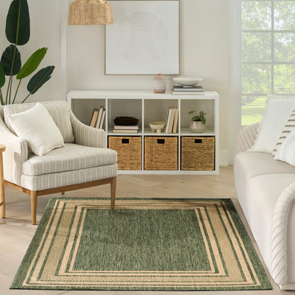 Neutral living room with white cube storage, wicker baskets, beige armchair, green bordered rug, plant, and framed art.