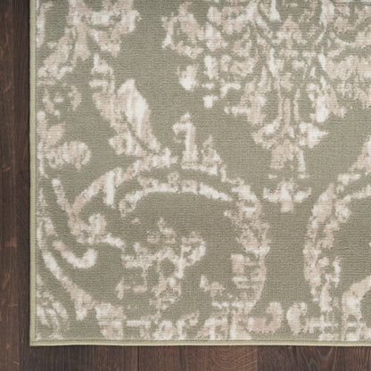 Muted sage-green damask rug with ivory floral motifs and light border on dark wood floor.