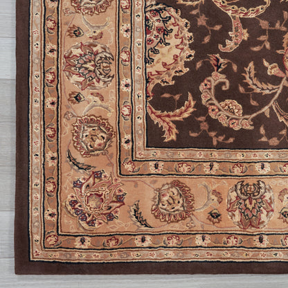 Close-up of an ornate oriental rug corner with cream, tan and brown hues and a floral border on a dark field.