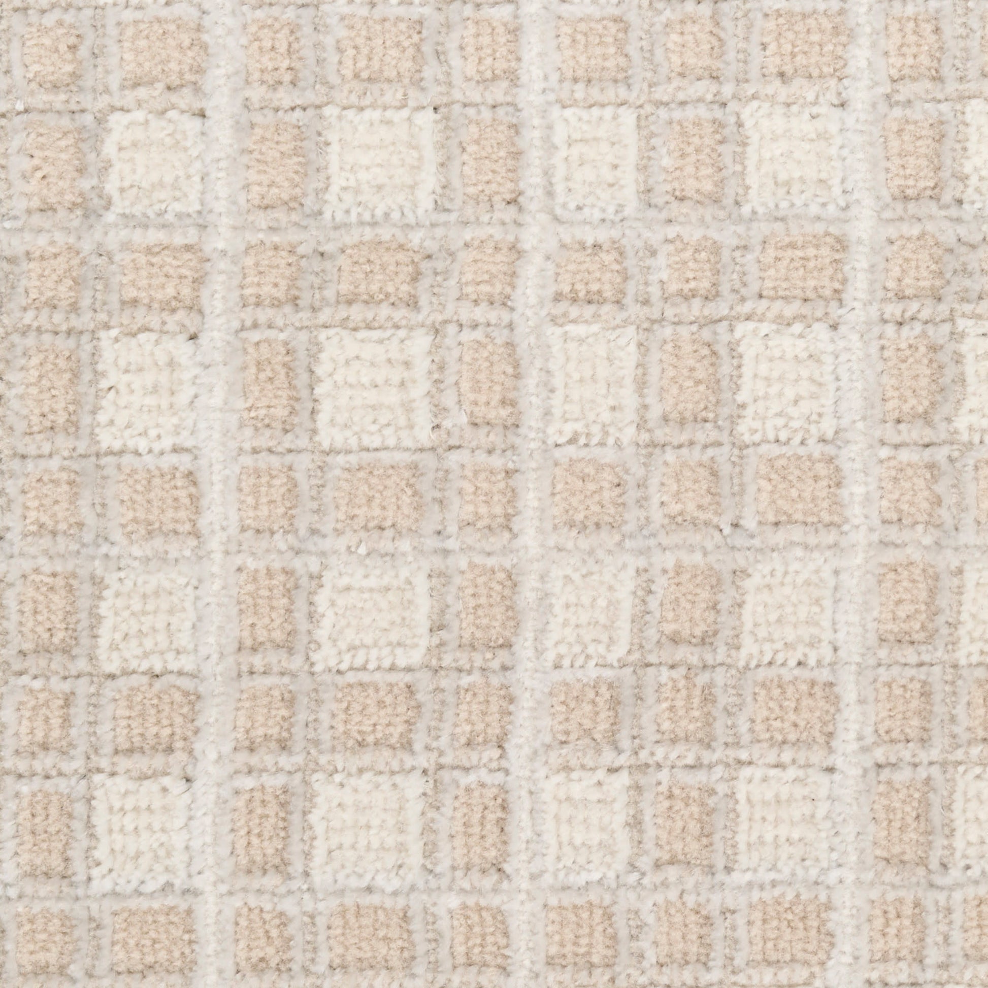 Beige and cream tufted rug close-up with a grid of soft square patches in neutral tones.