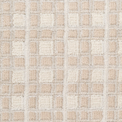 Beige and cream tufted rug close-up with a grid of soft square patches in neutral tones.