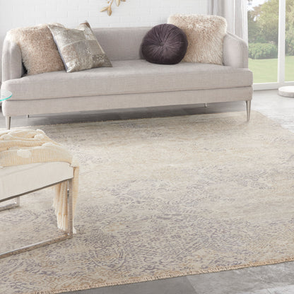 Beige patterned area rug on a bright contemporary living room floor, with a light gray sofa and metallic pillows nearby.