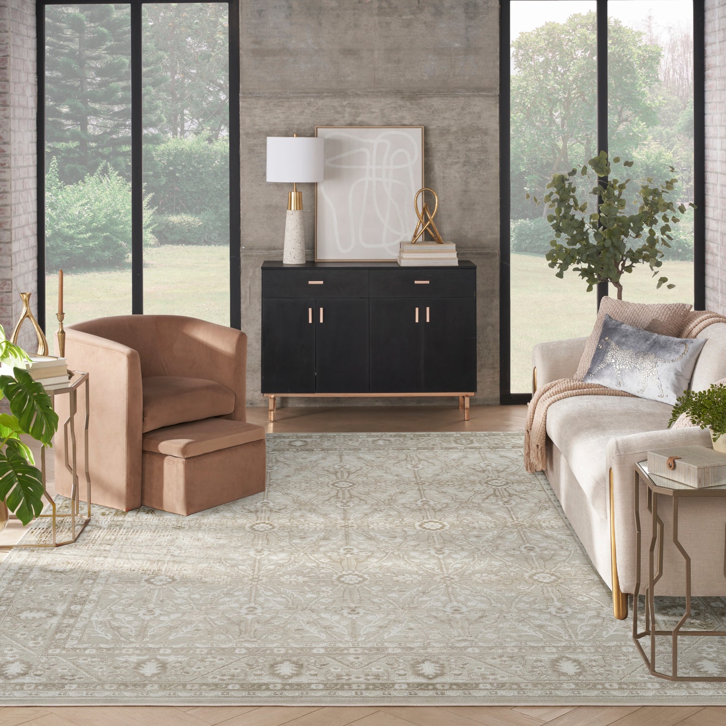 Modern living room with a black sideboard, blush armchair, beige sofa, gold accents, neutral patterned rug, large windows