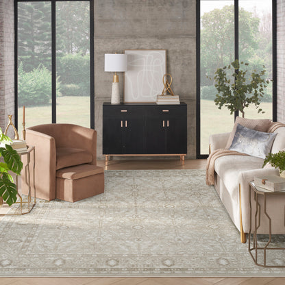Modern living room with a black sideboard, blush armchair, beige sofa, gold accents, neutral patterned rug, large windows
