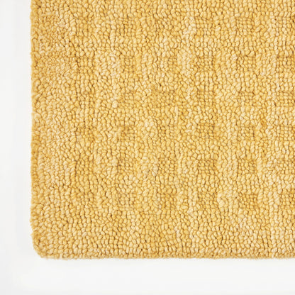 Golden beige boucle rug close-up with looped pile; soft textured floor mat for cozy interiors.