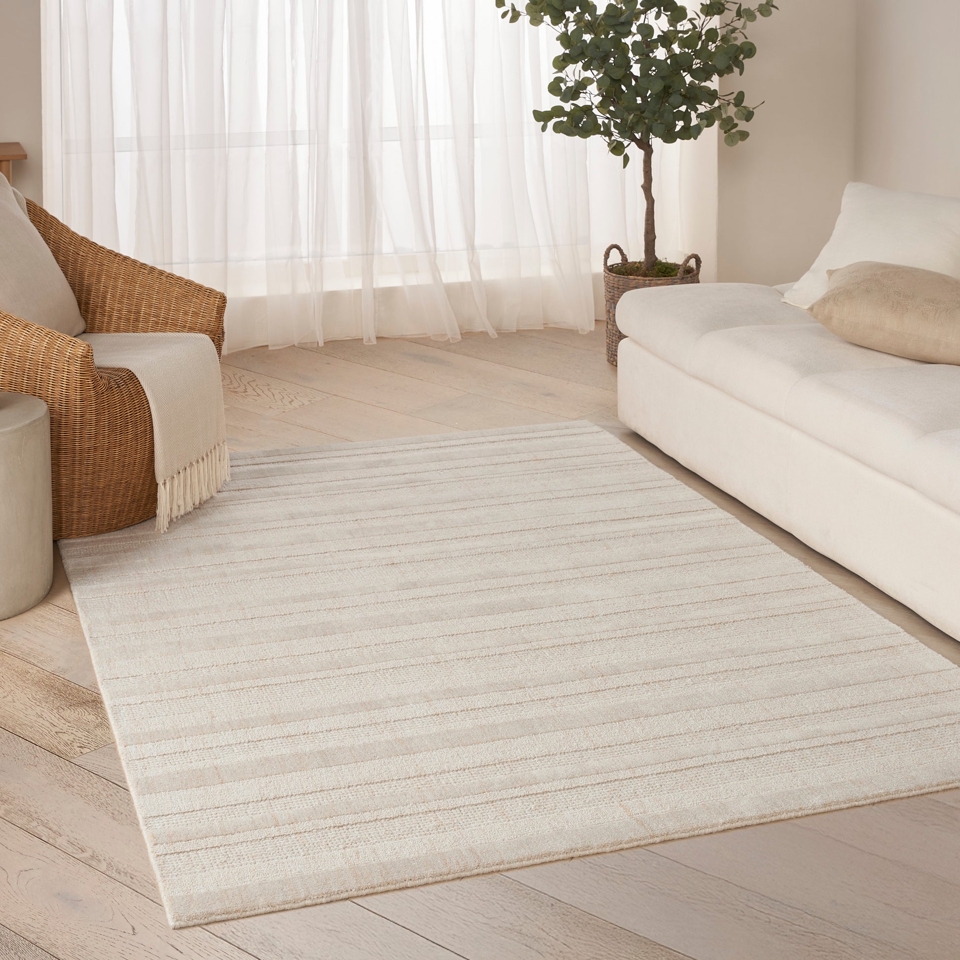 Cream woven rectangular area rug with subtle beige stripes in a light modern living room.