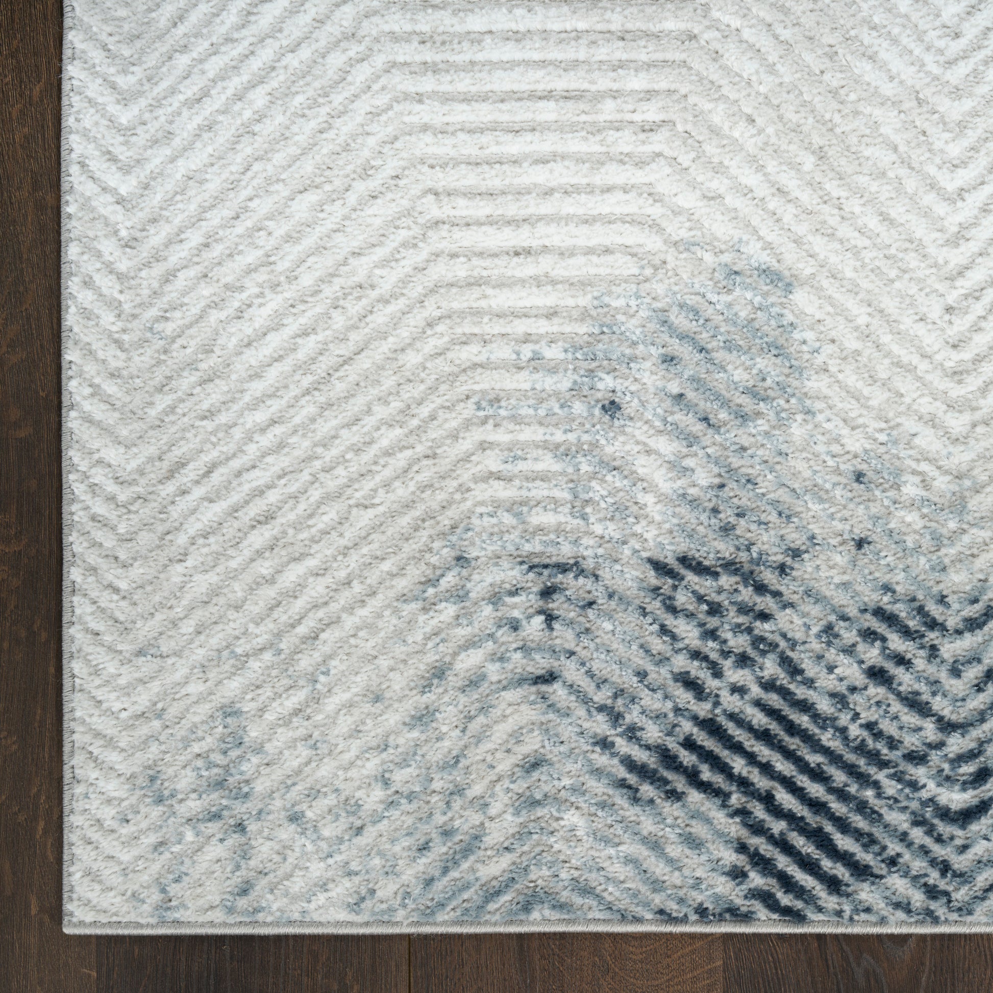 Cream and ivory textured area rug with subtle chevron lines and blue-gray abstract blotches, perfect for living rooms.