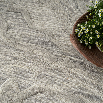 Grey textured rug with soft wavy pile; brown basket of white daisies sits along the edge.