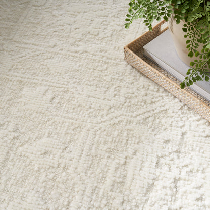 Cream textured rug with soft pile, a woven jute tray, and a potted fern for cozy home decor.