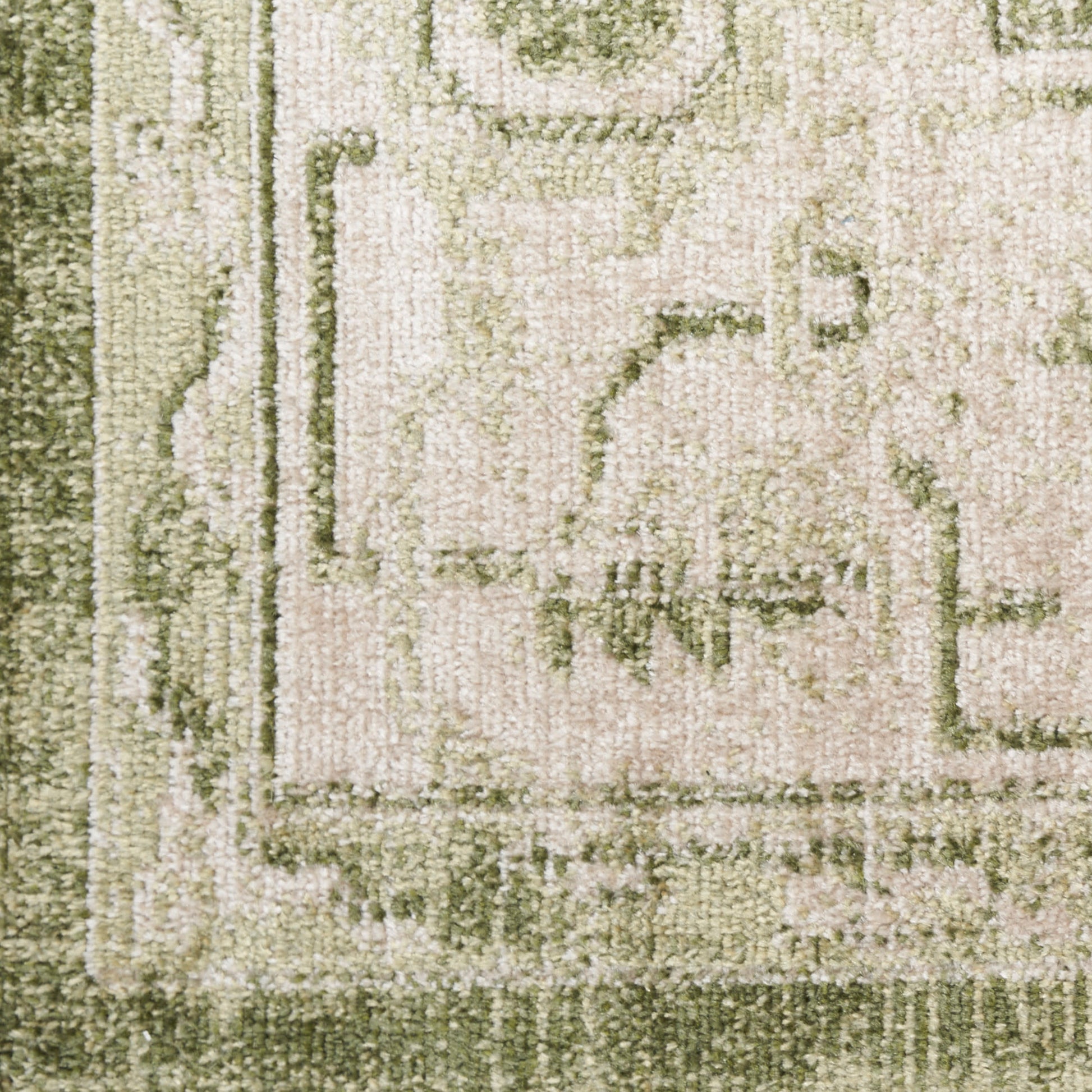 Close-up of an olive-green and beige patterned area rug with a textured pile and decorative border.