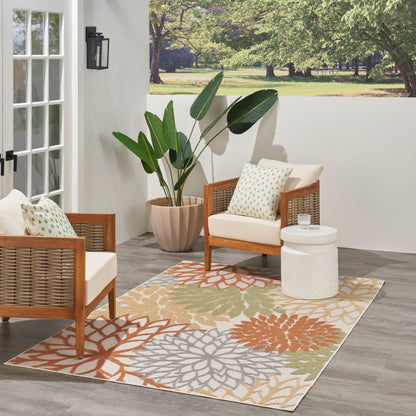 Outdoor patio with wicker armchairs, beige cushions, a multicolor floral rug (5' x 8'), a white round table, and a large potted plant.