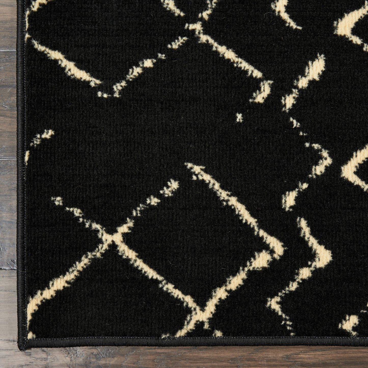 Rectangular black rug with ivory diamond lattice pattern; low-pile, modern geometric decor for living room.