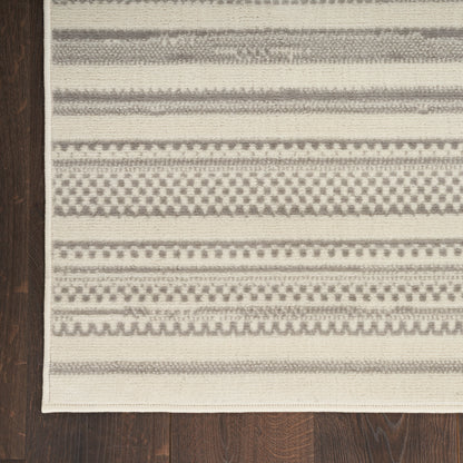 Rectangular beige and gray woven rug with geometric stripes and a cream border on dark wood floor.
