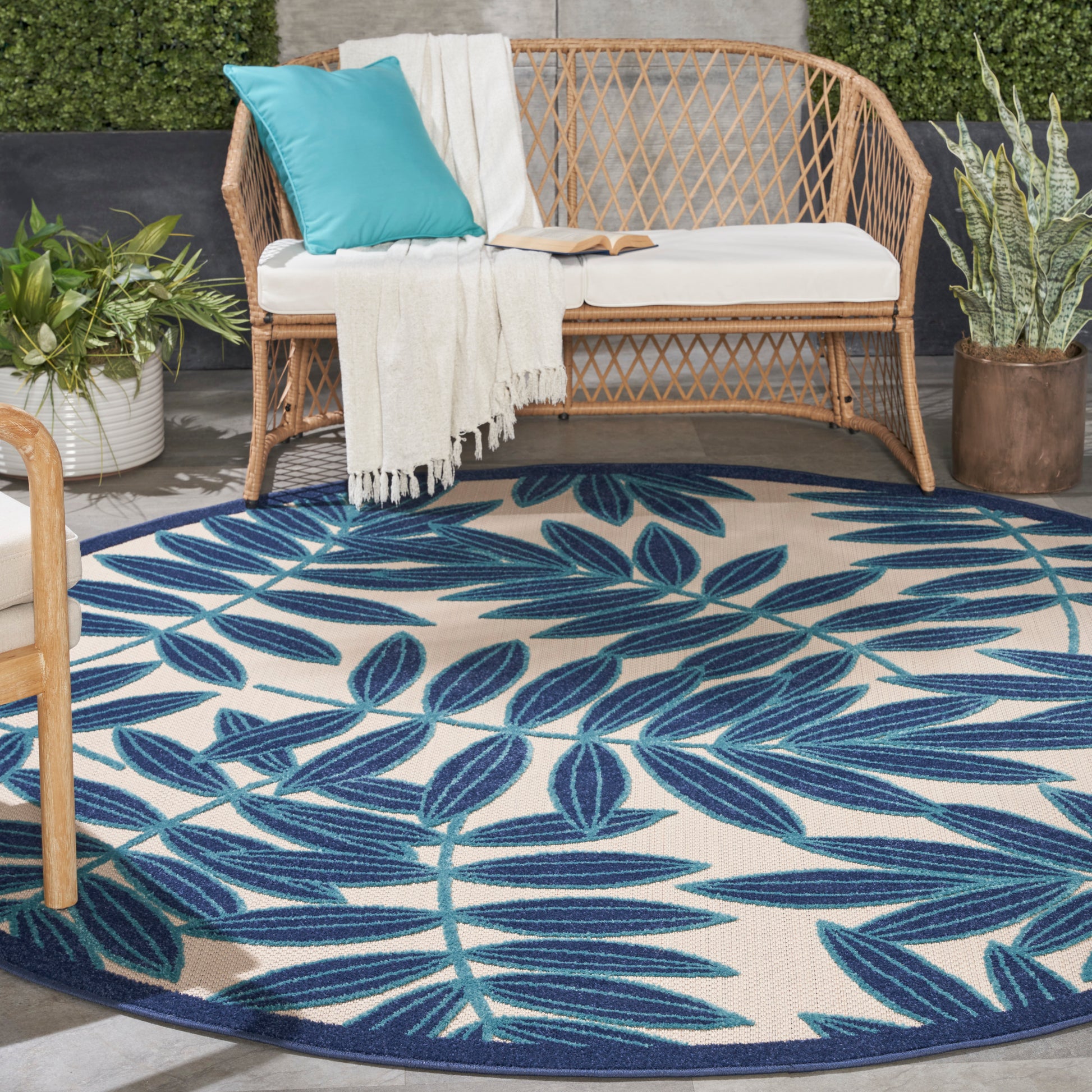 Round tropical outdoor rug with blue leaf pattern on cream.