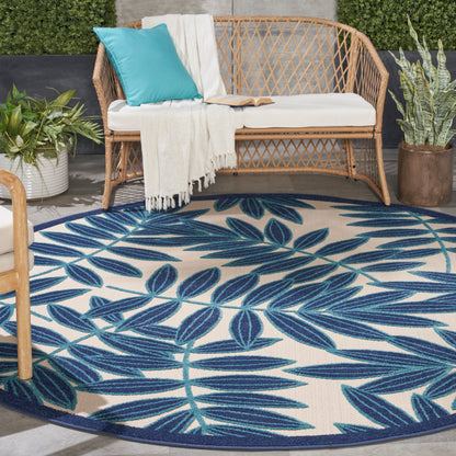 Round tropical outdoor rug with blue leaf pattern on cream.