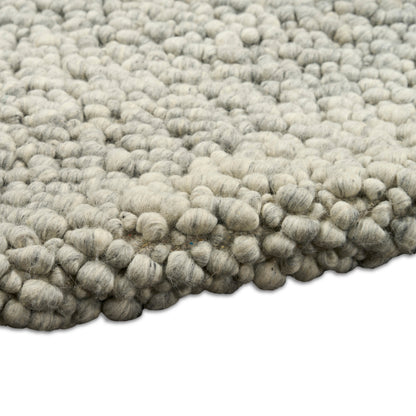 Light gray wool boucle rug with chunky knobby loops, dense textured surface for cozy floor decor.