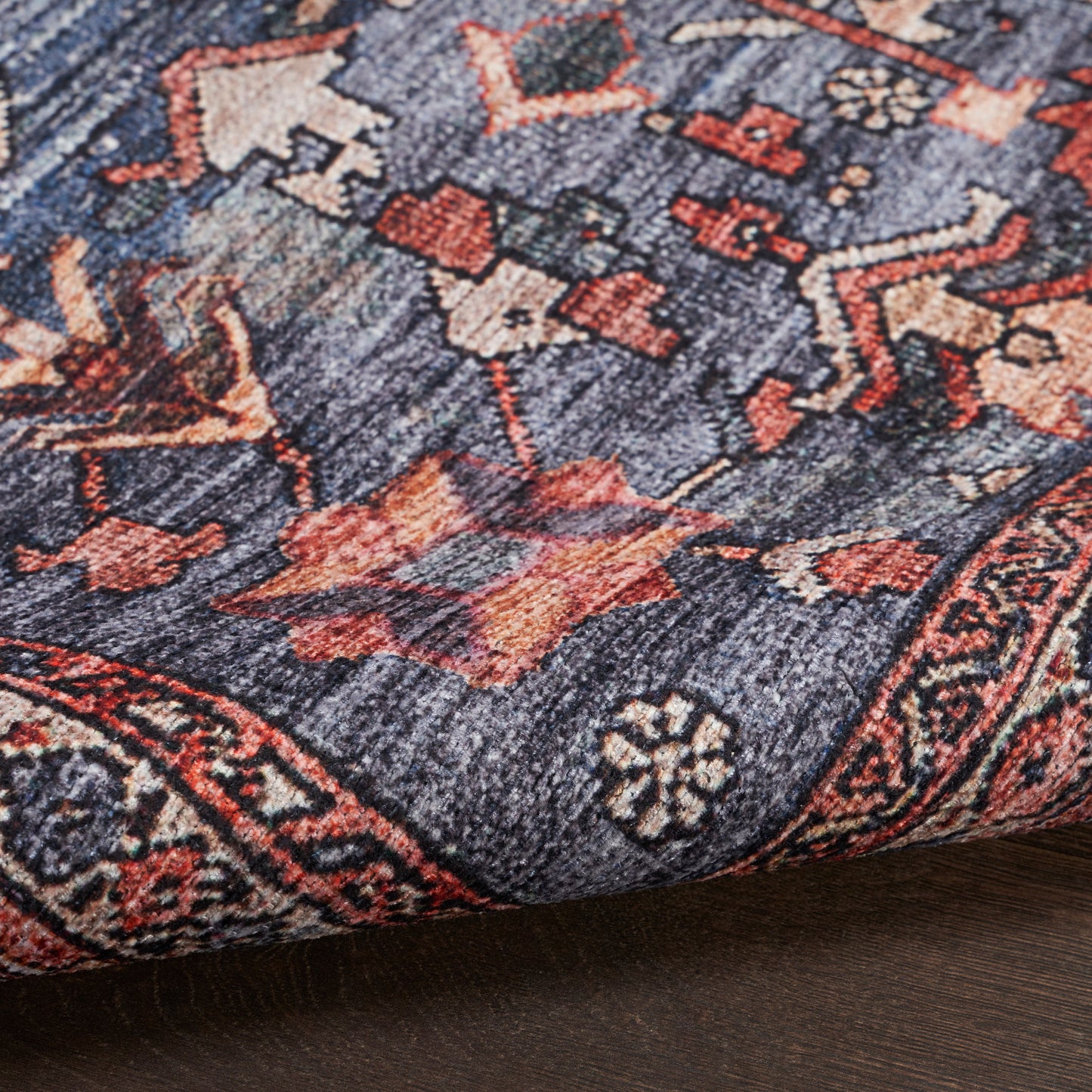 Close-up of a navy blue oriental rug with red and ivory floral motifs and a decorative border.