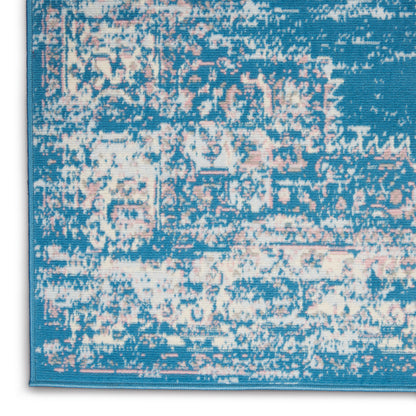 Close-up of blue distressed patterned rug corner with pink and cream accents and turquoise border.