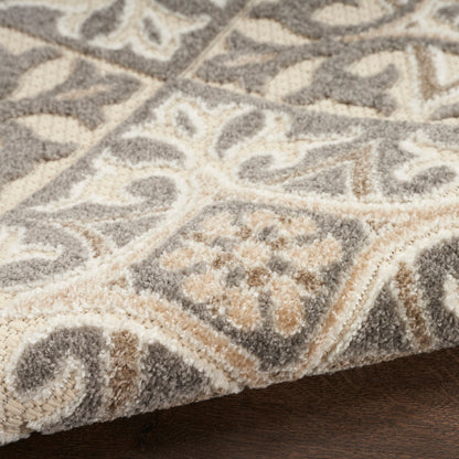 Close-up of a plush gray and cream patterned rug with border, damask motif, soft shag texture.