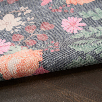 Floral woven fabric with pink, peach and white flowers and green leaves on indigo background; folded edge.