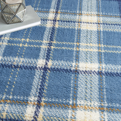 Blue plaid wool rug with cream and rust lines; cozy decor setup with a geometric metal candle holder on books.