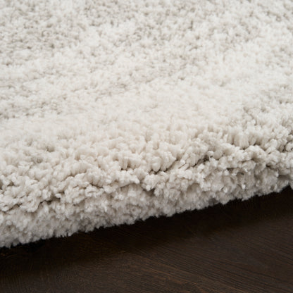 Cream shag rug with dense fluffy pile on dark hardwood floor; cozy modern area rug.