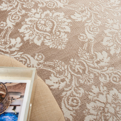 Beige-brown damask area rug with ornate floral pattern; partial view of a glass-topped coffee table on a wooden floor.