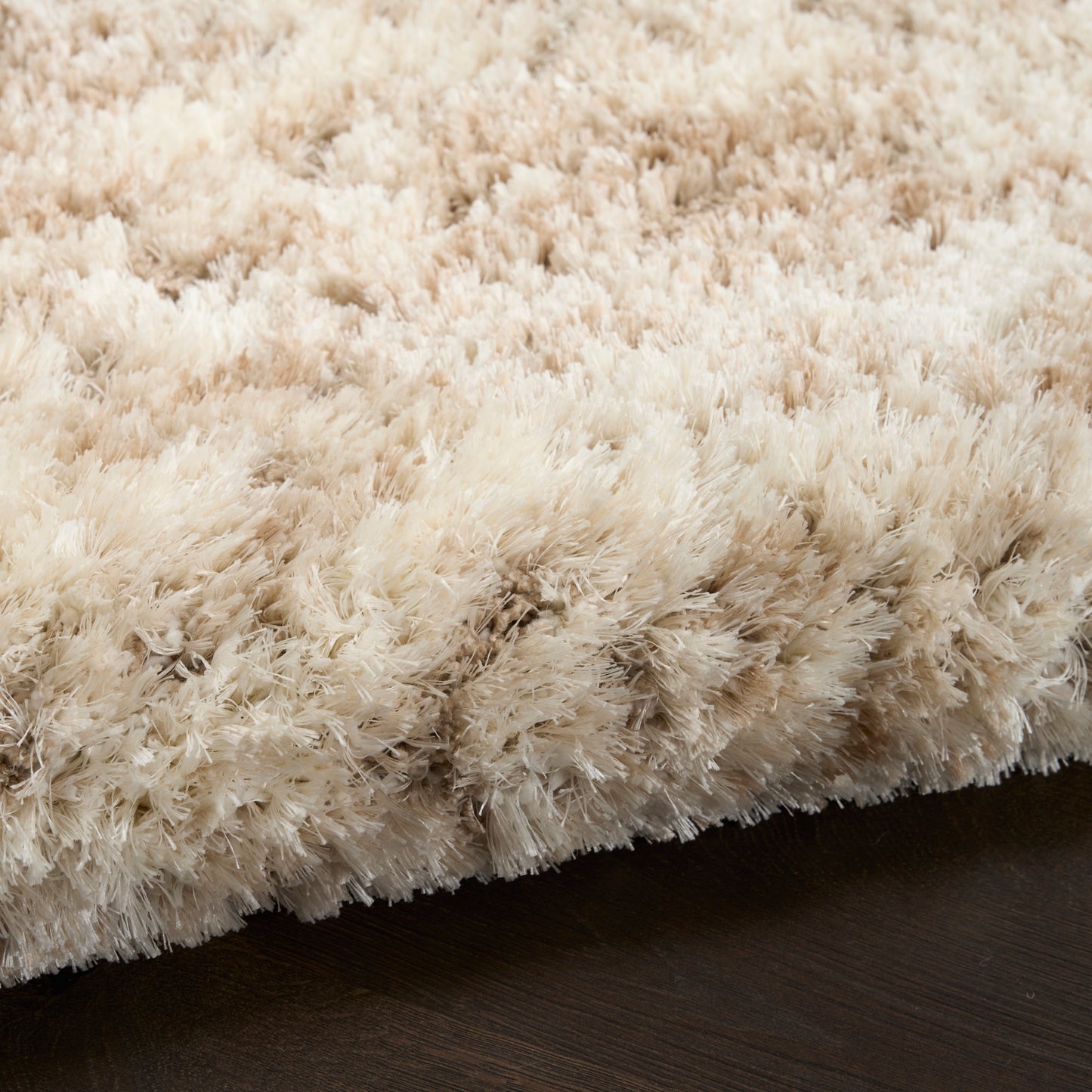 Cream beige shag rug with a thick fluffy pile laid on dark wood floor.