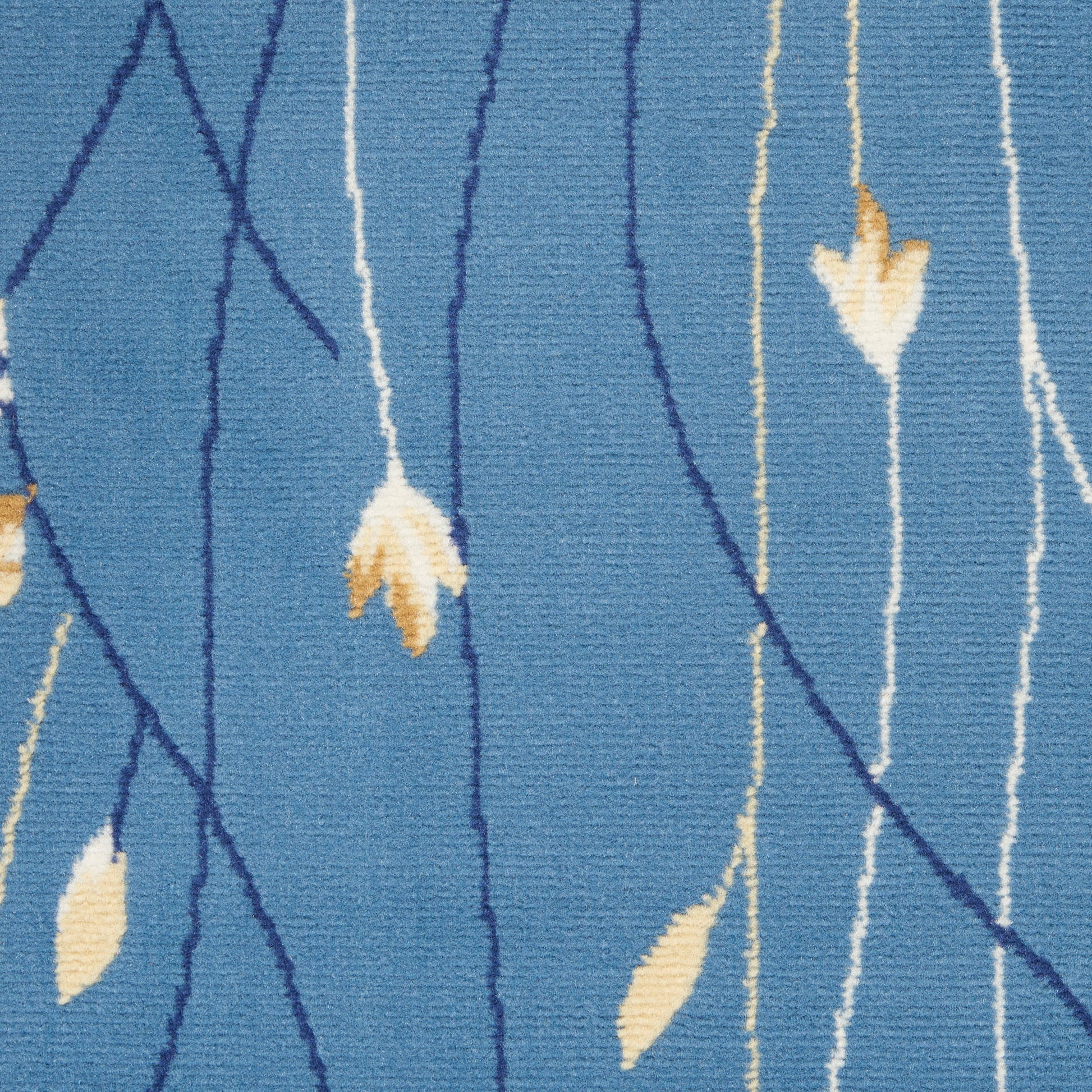 Blue woven rug close-up with dark blue stems, pale yellow leaves, and cream vertical lines.