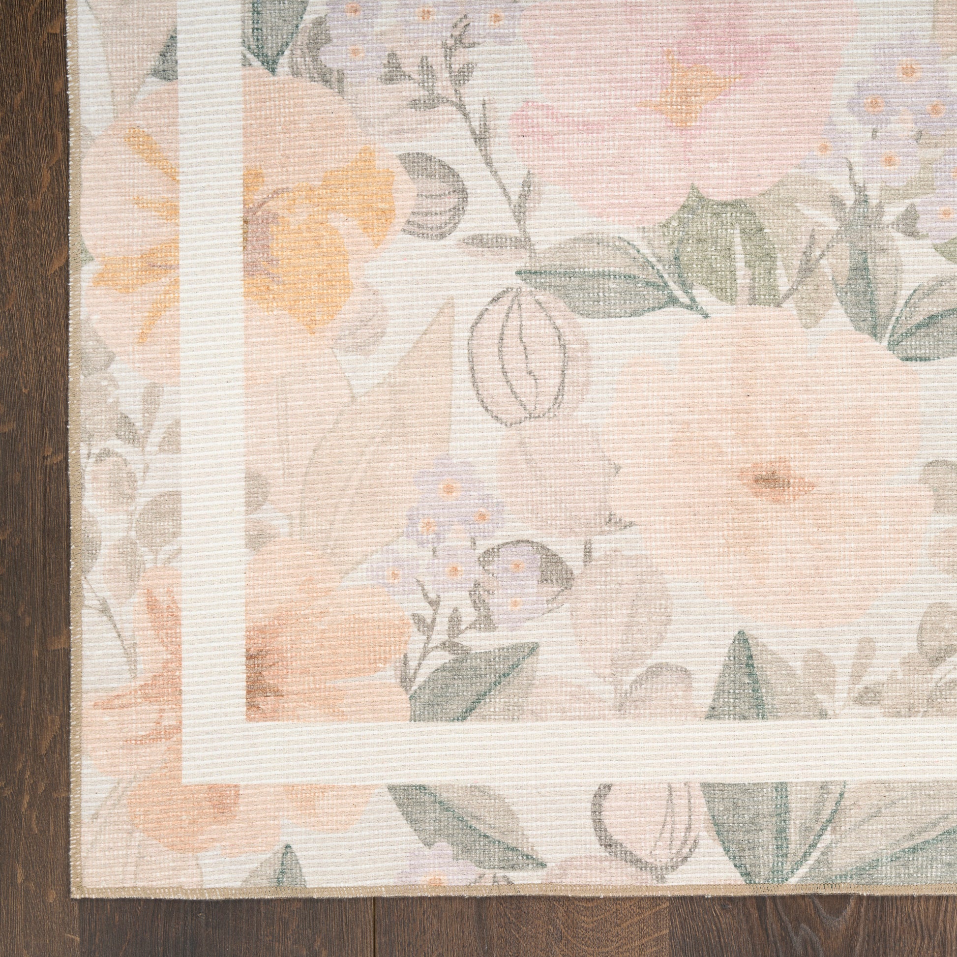 Pastel floral rug with peach and pink blossoms, green leaves, white inner frame, on dark wood floor.