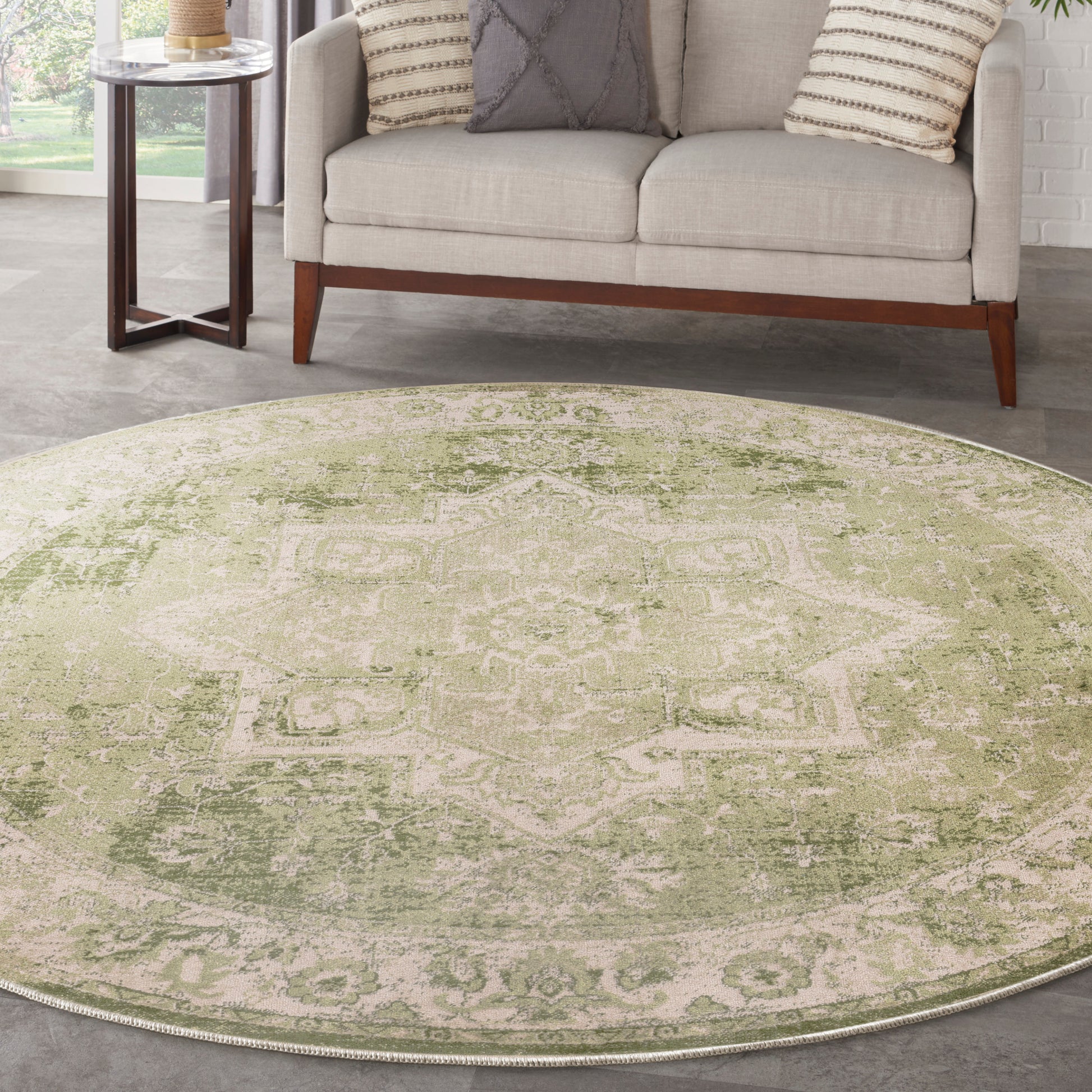 Round green distressed oriental rug in a living room with a beige sofa and textured pillows.